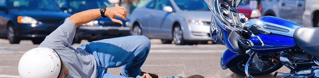 man on the ground next to a motorcycle after being in an accident