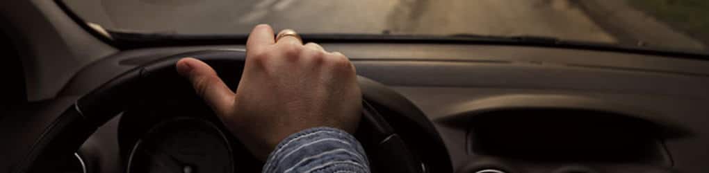 8 simple steps to avoid injury in a car crash - man driving a car with view of the steering wheel