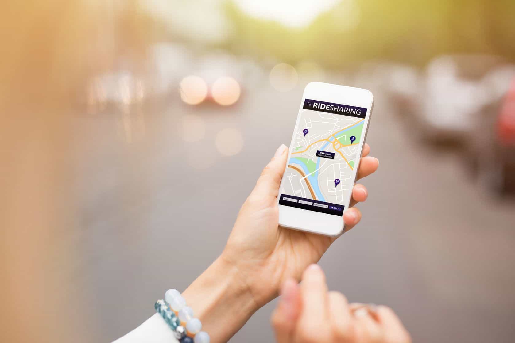 person holding their phone looking at a ride share app