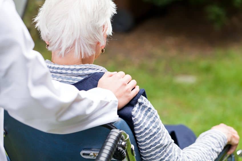 Photo of young carer pushing an elderly woman in a wheelchair