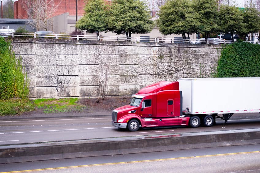 red semi truck driving down the road
