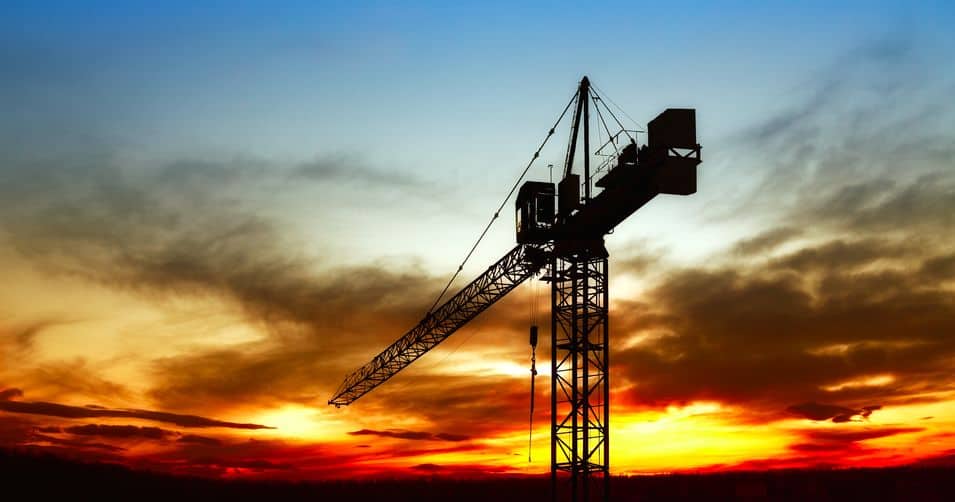 silhouette of a construction crane with a sunset in the background
