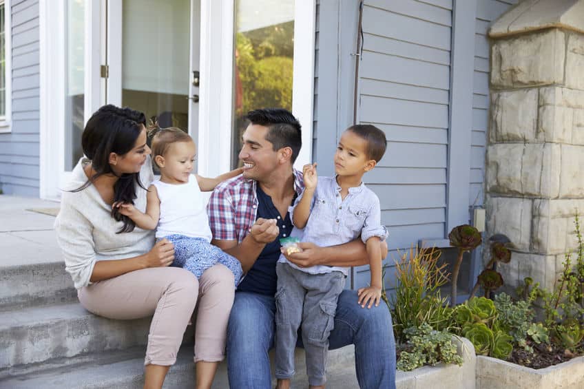 happy family sitting on the front steps of their house