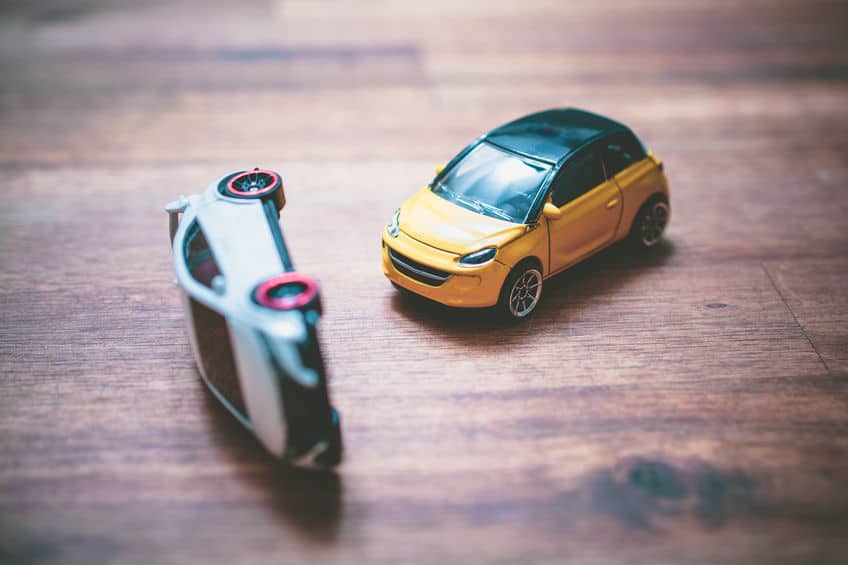 toy cars simulating an accident where on is flipped on its side