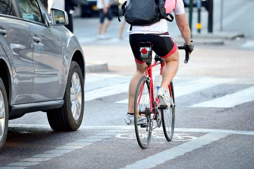 rear view of bicyclist in the bike lane wearing a backpack