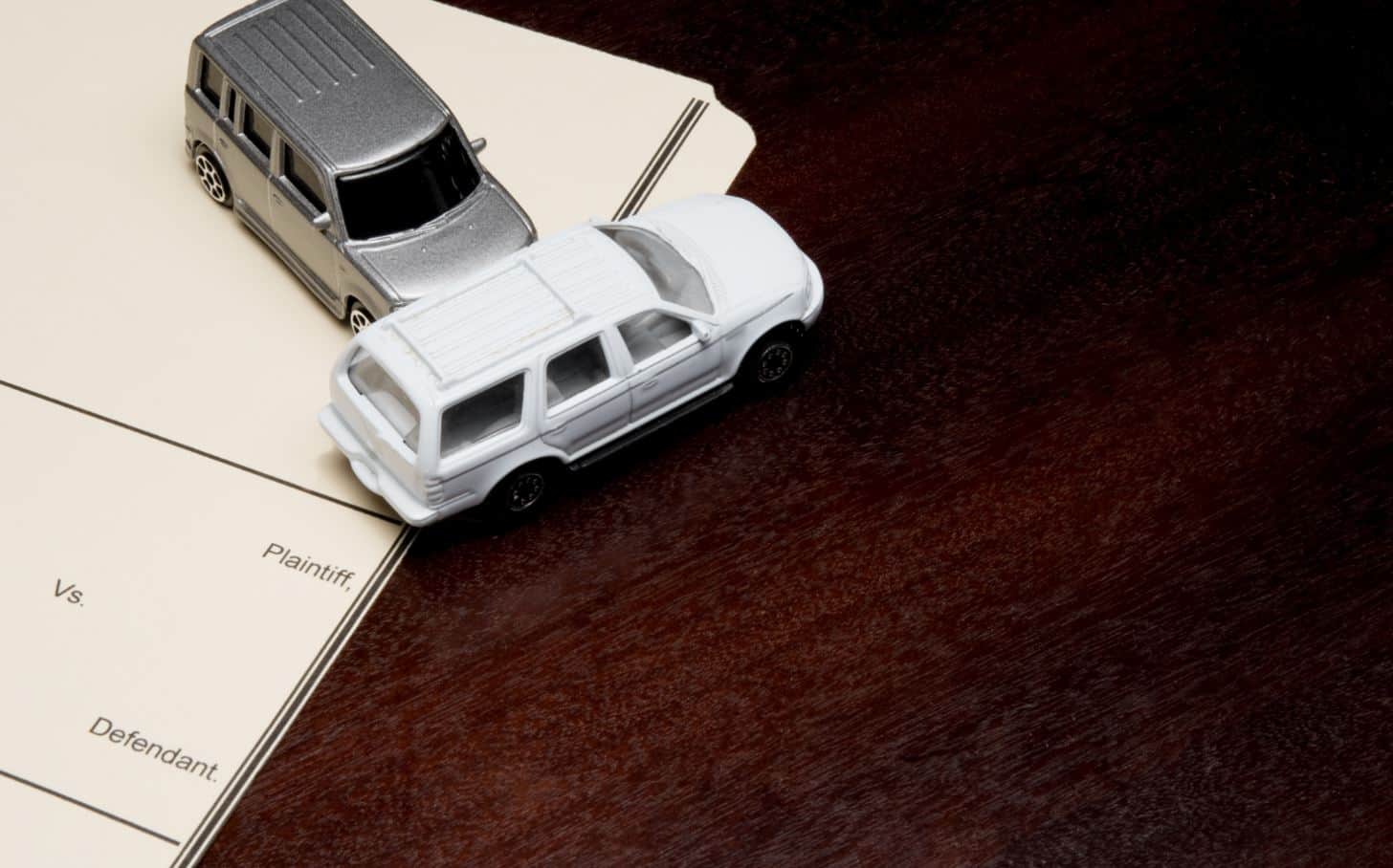 two toy cars demonstrating a t-bone crash on a desk and legal paperwork