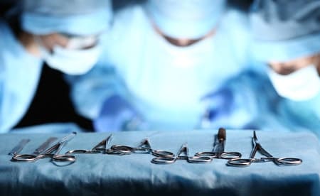 surgical instruments on a table with surgeons working in the background