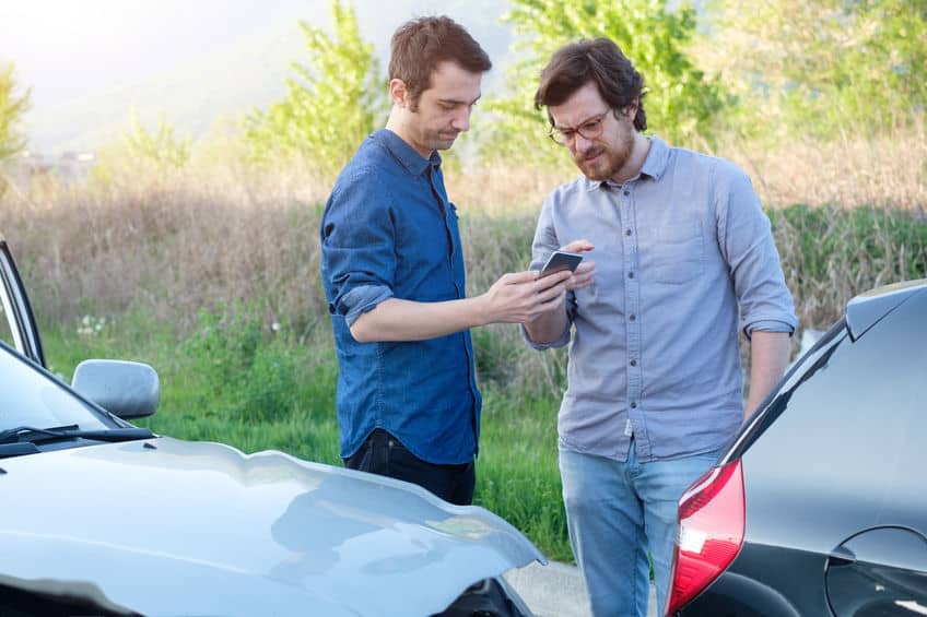 two men taking pictures of their cars after a car accident