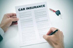 person signing a car insurance document