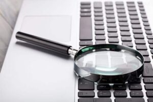 laptop keyboard with magnifying glass on top of it