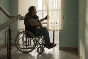 elderly man sitting in wheelchair looking out window