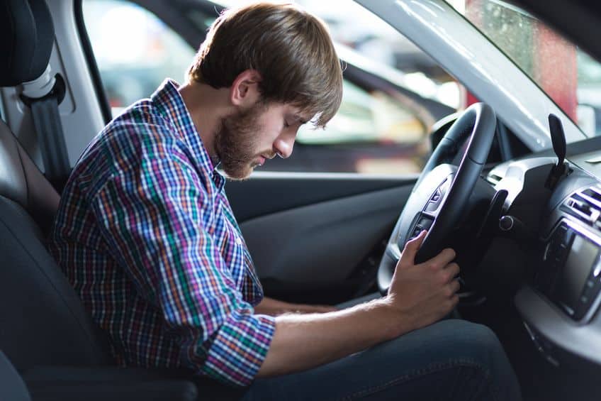 tired man falling asleep at the wheel of his car