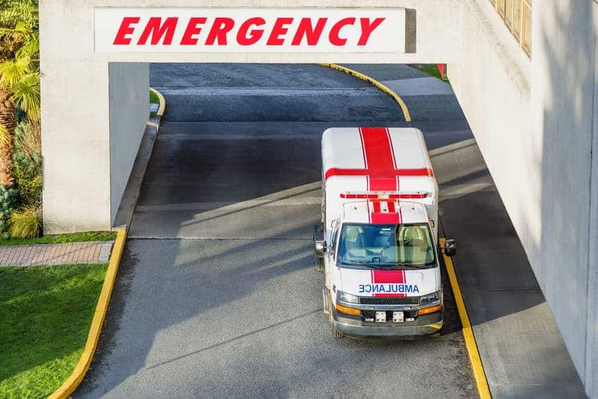 a view from the top of the entrance to the hospital and a modern ambulance with a red cross parked near the emergency entrance