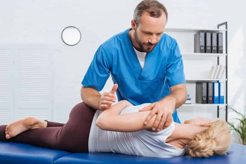 chiropractor adjusting a patient's back while in their office