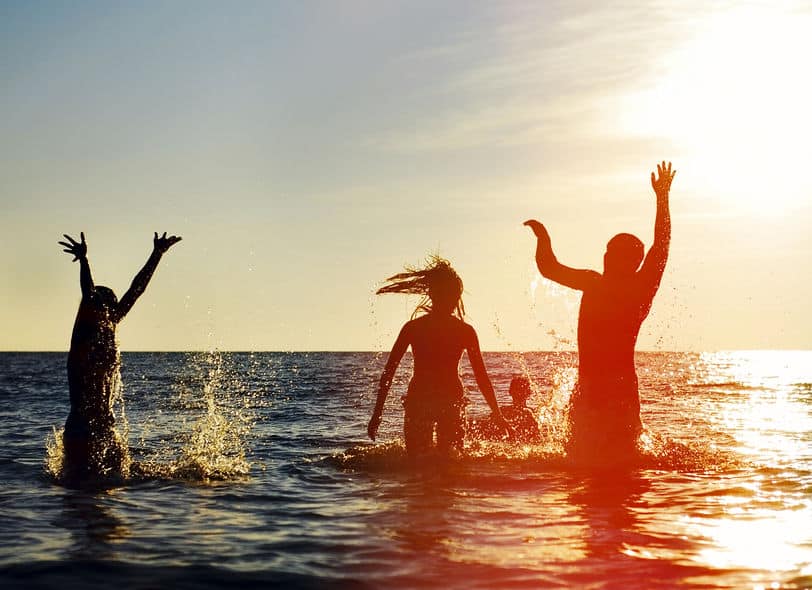 silhouettes of young group of people jumping in the ocean