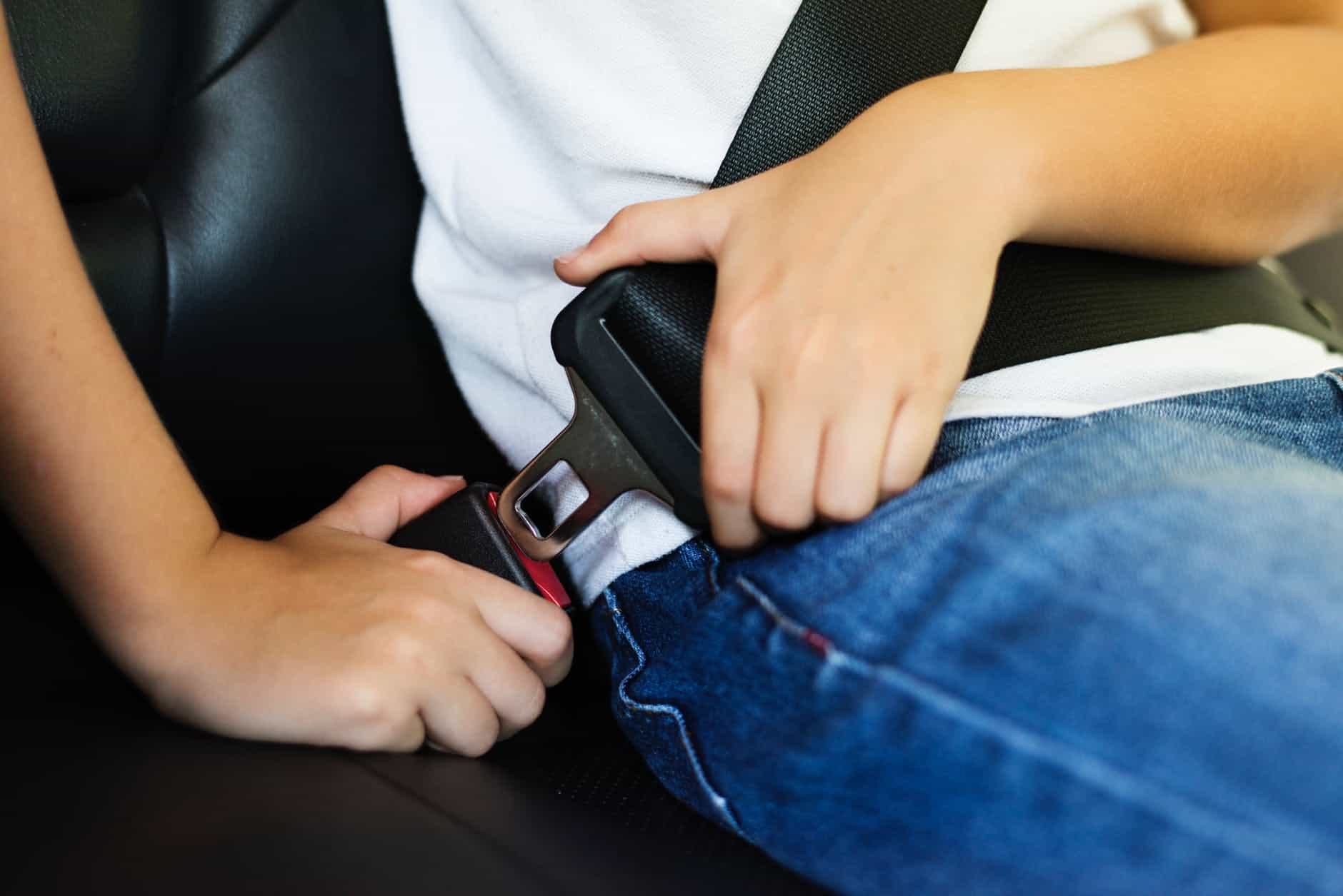 person buckling seatbelt in car