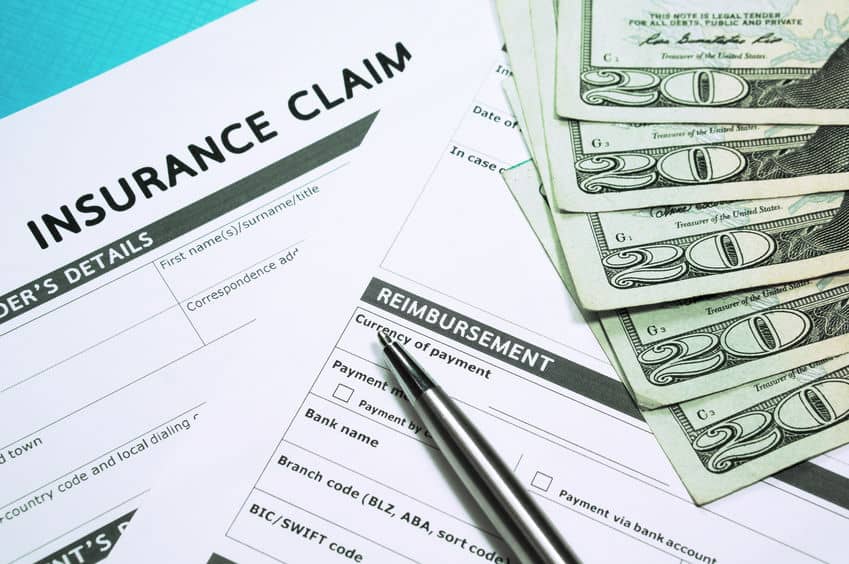 car insurance claim forms with a pen and money on a table