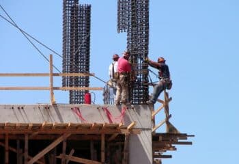 construction workers on the top of a building site, strapped into scaffolding for safety