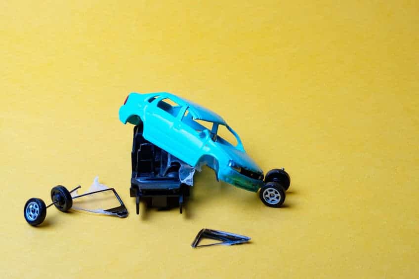 toy car broken into pieces after , wheels and glass fell off, yellow background