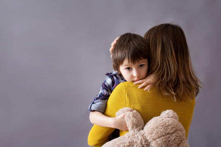 sad little child, boy, hugging his mother at home, holding a teddy bear in one hand