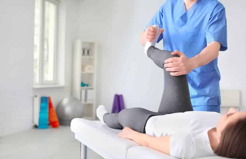 Physiotherapist working with a patient on their leg and knee in a clinic