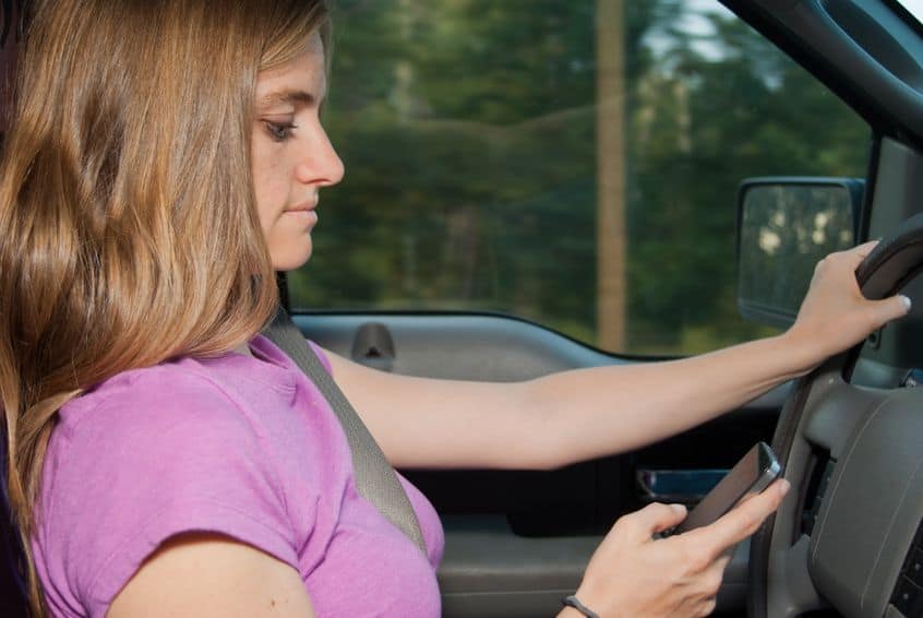 woman texting and driving in a car during the day