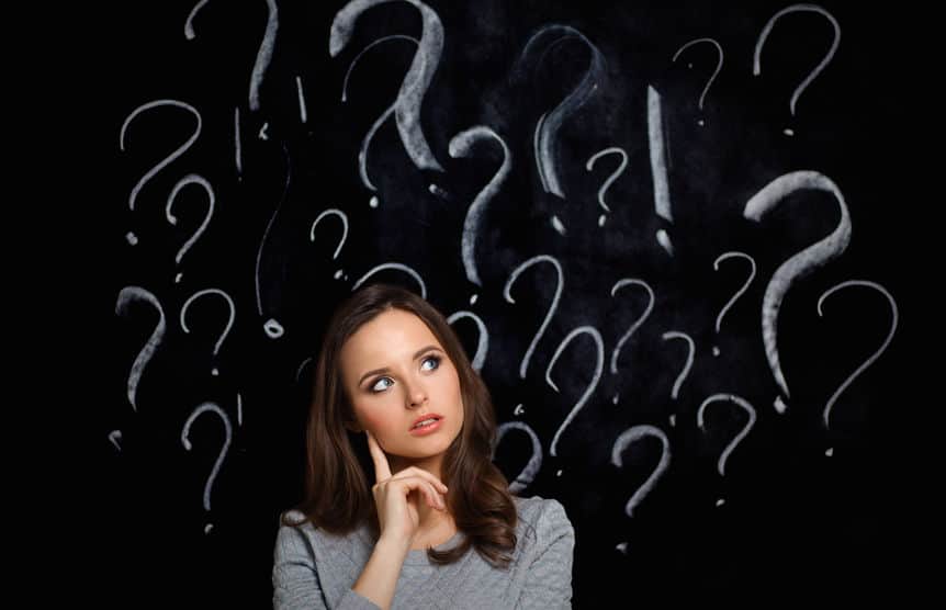 woman standing in front of a chalboard with question marks drawn in chalk around her head