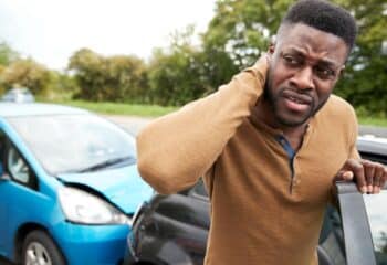 Male Motorist With A Whiplash Injury after a Car Crash Getting Out Of the Vehicle before calling The Barnes Firm Injury Attorneys