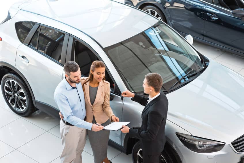 view of a rental car employee and couple signing the paperwork for a car rental
