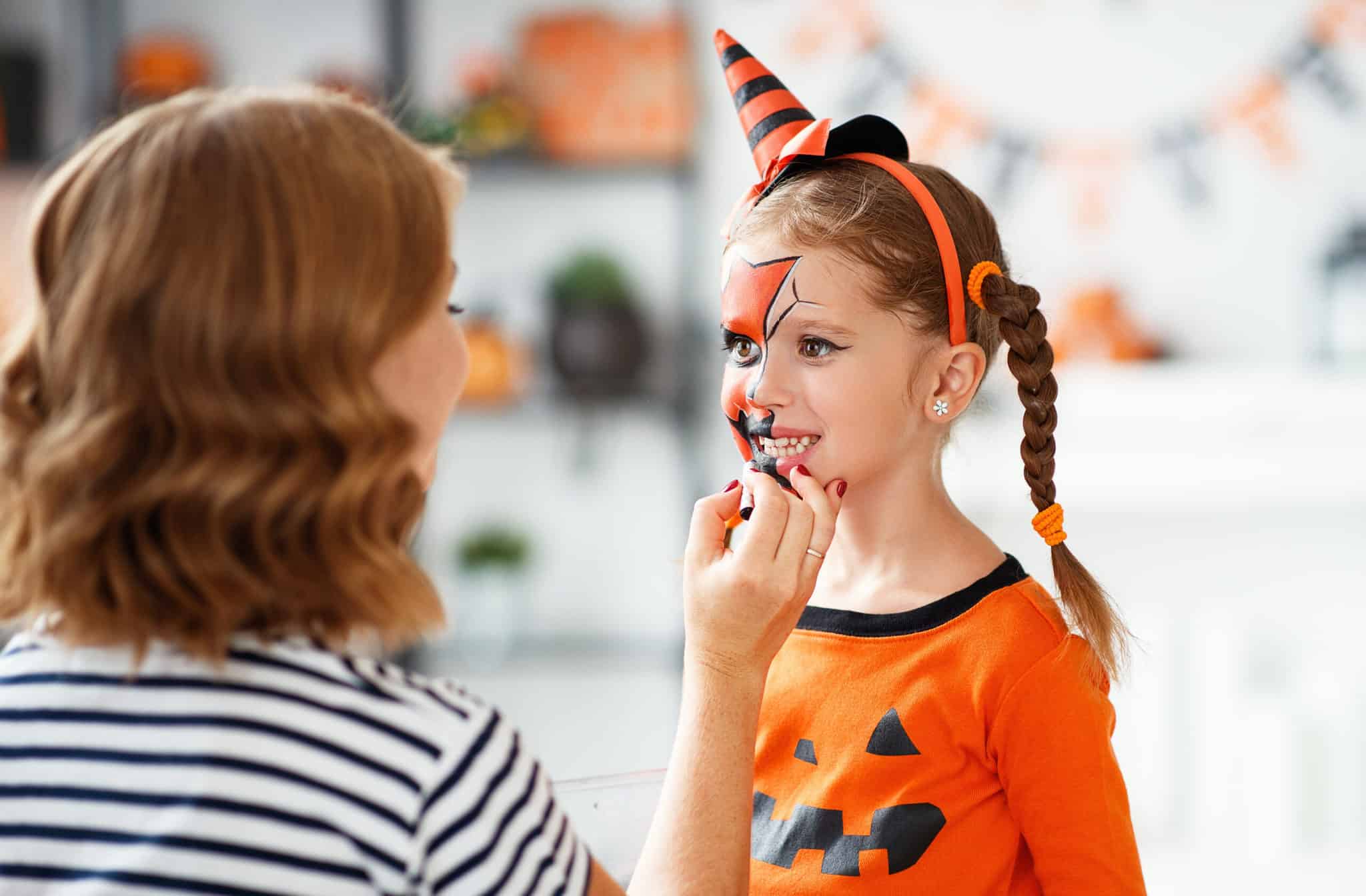 woman getting child ready for halloween with face makeup