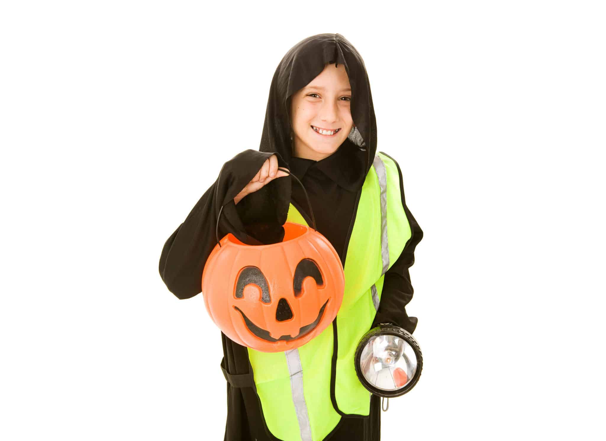 child in a black halloween costume with a reflective vest, candy basket, and flashlight